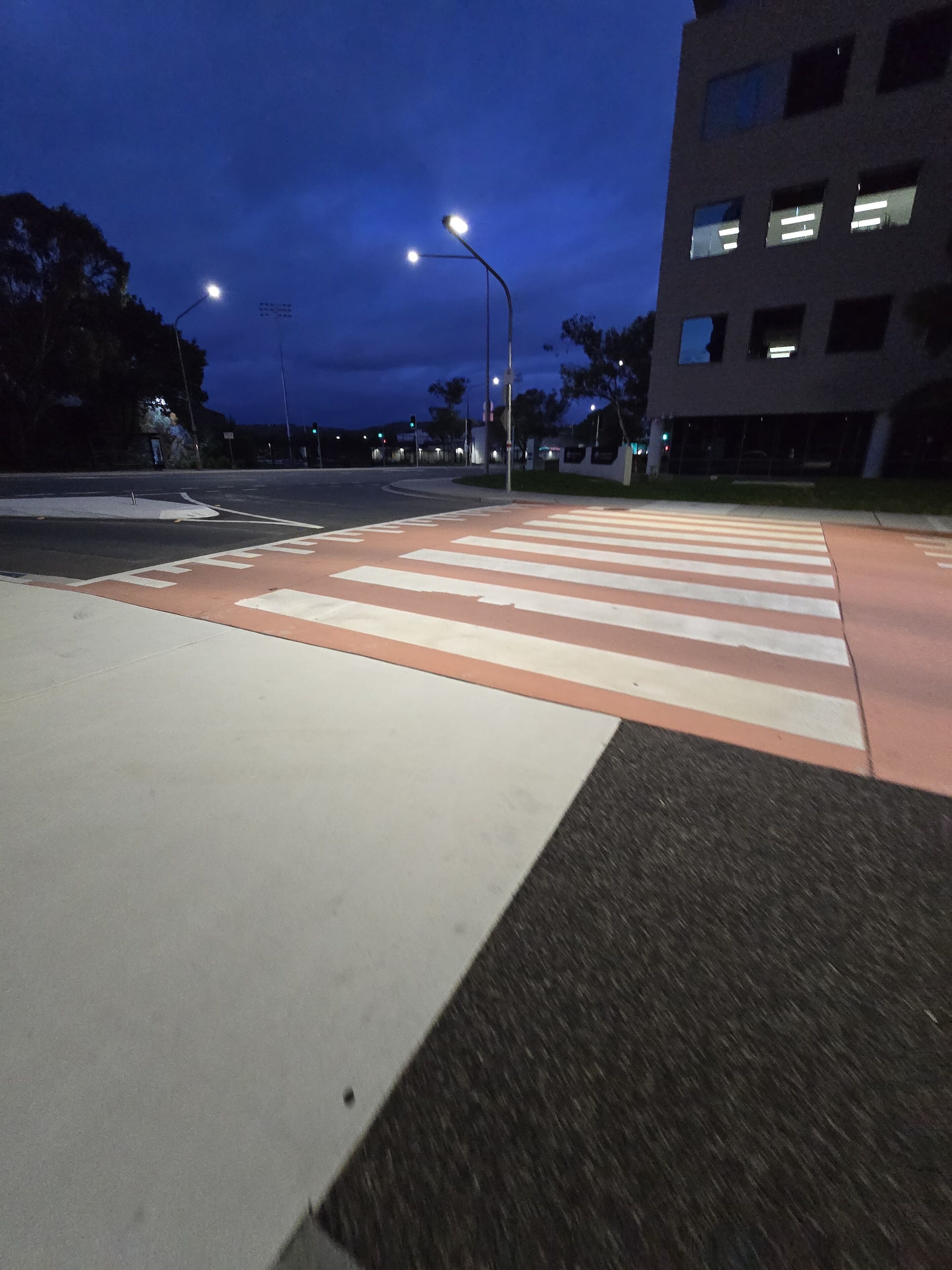 Eine Fußgängerstrecke mit Zebrastreifen, Straßenlaternen und einem Gebäude im Hintergrund.
