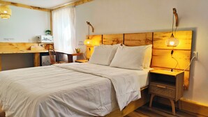 Una cama bien hecha con sábanas blancas, cabecera de madera y dos lámparas de noche.