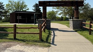 A rustic wooden archway leading to a small building with a sign that reads "HAPPY STREETS."