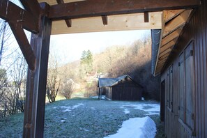 A wooden barn with a sloped roof and a covered area with wooden beams.