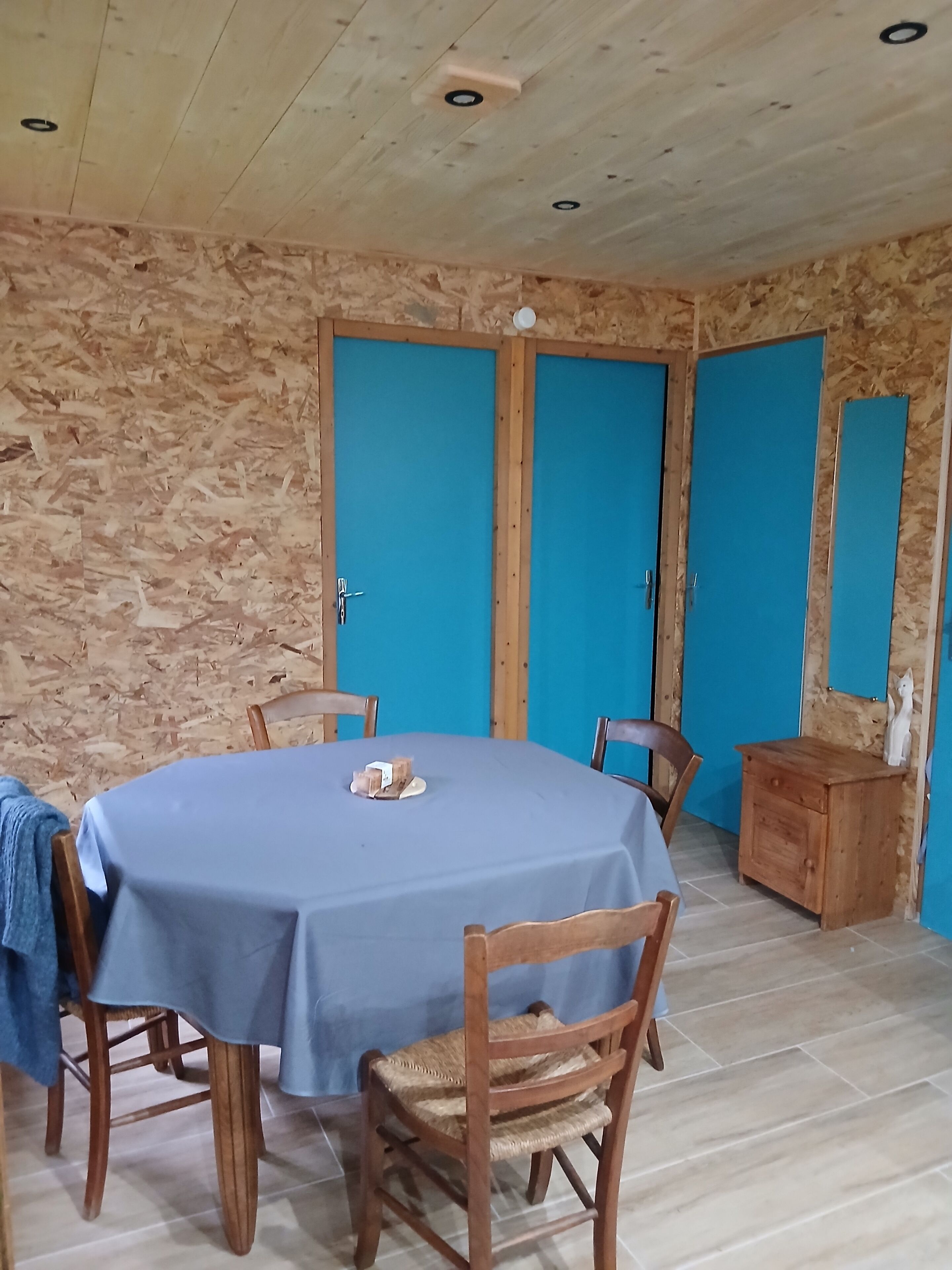 Una zona de menjador amb una taula rodona, cadires i un armari de fusta.