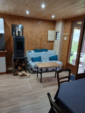 A cozy room with a wooden interior, a sofa with blue cushions, a small table, and a wood stove.