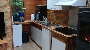 Una cuina compacta amb armaris de fusta, un fogó integrat i una cafetera.