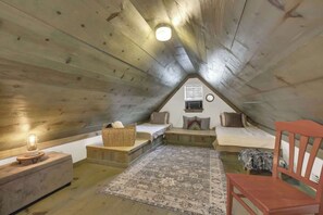 A cozy attic bedroom with a sloped ceiling, a bed, a small table, a chair, and a rug. - Cactus Flower Lodge-Pet Friendly-Starlit Sky Views (Fredericksburg)