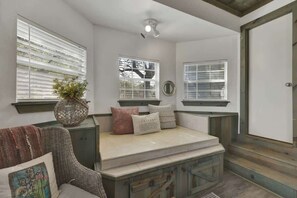 A cozy room with a built-in bench, large windows, and a wicker chair.