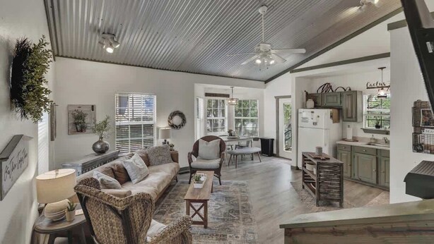 A spacious living room with a sofa, armchairs, and a coffee table. There is a kitchen area with cabinets and a countertop visible through an open doorway. - Cactus Flower Lodge-Pet Friendly-Starlit Sky Views (Fredericksburg)