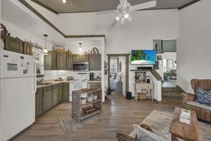A spacious living area with a kitchen, dining area, and a staircase leading to an upper level.