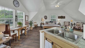 A spacious loft bedroom with a large bed, a skylight, and a view of the outdoors. - Cactus Flower Treehouse-Pet Friendly-Scenic Views! (Fredericksburg)