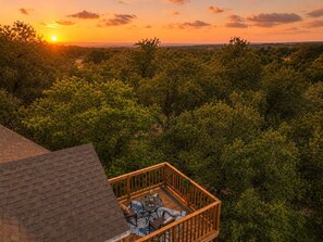 Un balcón con vistas a un paisaje boscoso durante el atardecer.