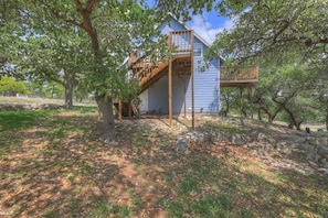 A house with a wooden deck and a staircase leading to a second-story balcony.