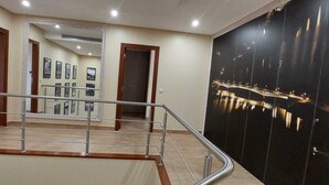 A hotel lobby with a staircase, a black wall with a cityscape mural, and framed pictures on the wall.