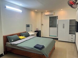 Ein Schlafzimmer mit Bett, Nachttisch, Schreibtisch, Kleiderschrank und Klimaanlage.