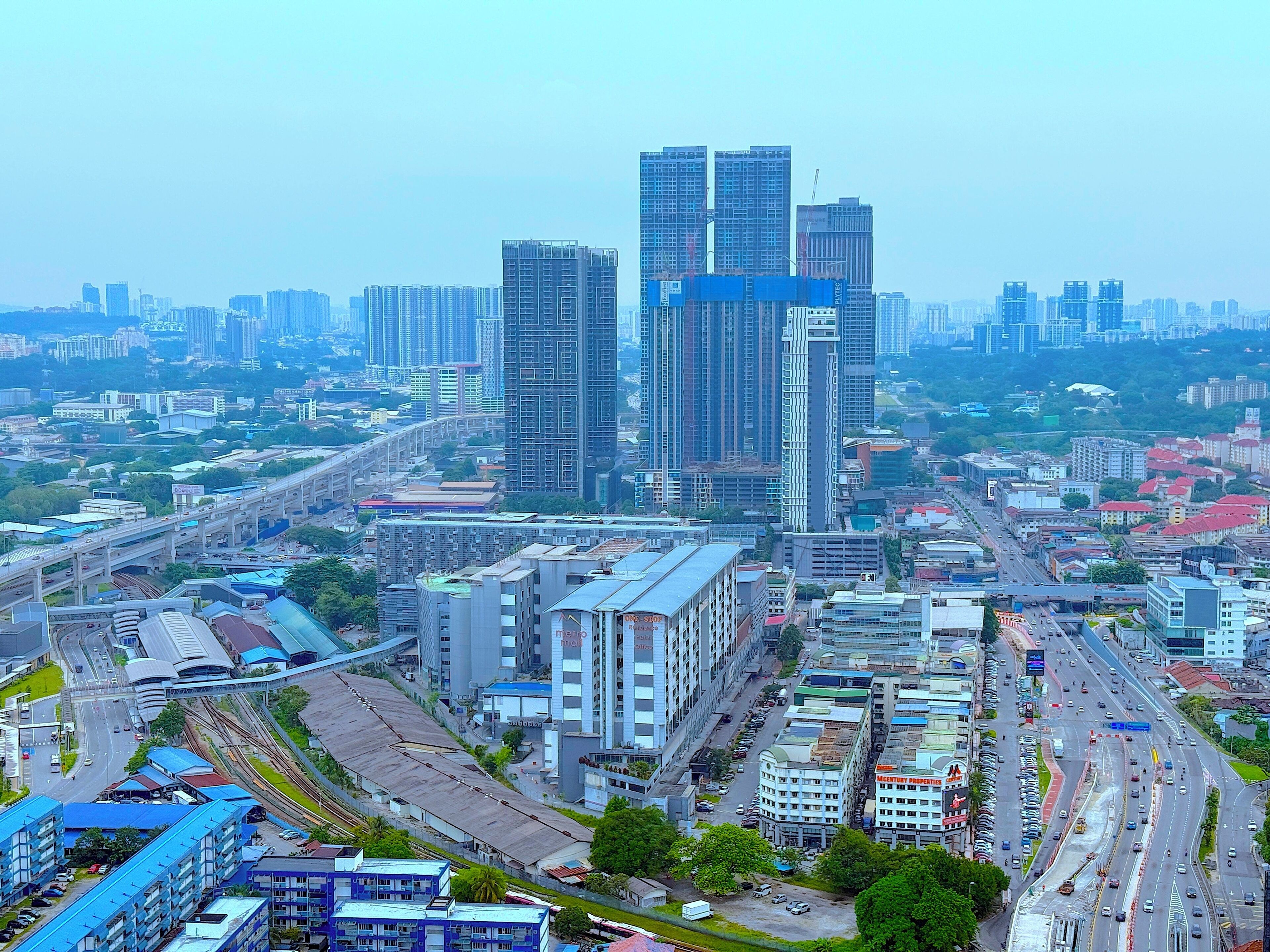 A cityscape with modern high-rise buildings, a busy highway, and a mix of commercial and residential structures.