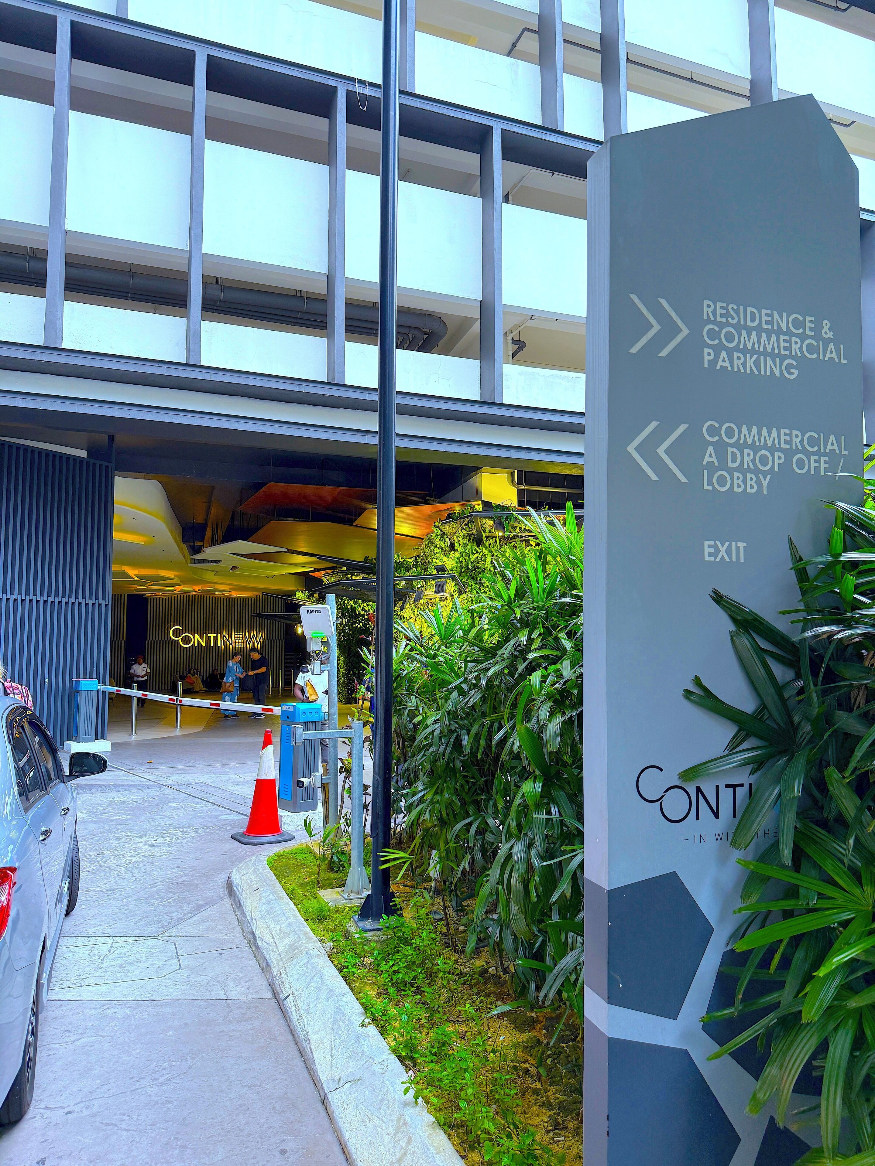 A modern building entrance with directional signage for 'Residence & Commercial Parking' and 'Commercial A Drop Off / Lobby'.