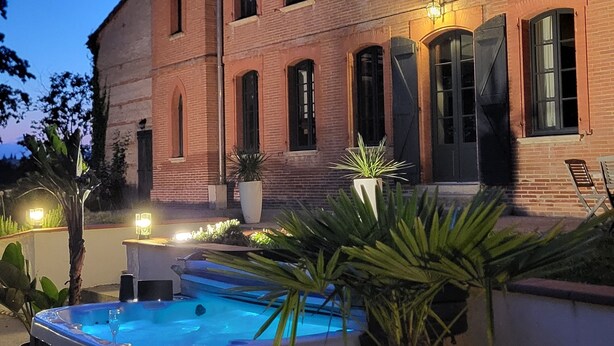 A large brick building with a swimming pool and hot tub in the foreground. - Castle 15mn Toulouse Pyrénées' view and pool (Clermont-le-Fort)