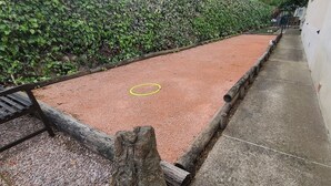 Zona de ejercicio roja con un banco, un poste de madera y un camino de hormigón.