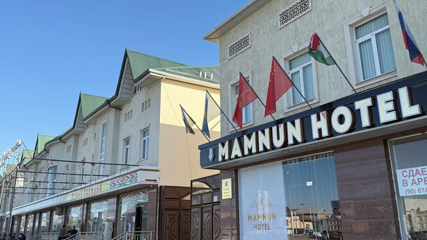 Een hotel met een bord waarop 'MAMNUN HOTEL' staat en verschillende vlaggen.