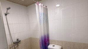 Een badkamer met een douche, toilet en wastafel.