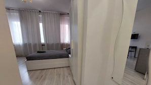 A bedroom with a bed, a large mirror, and a view of a living area. - Magheru Studio Central (Bucharest)