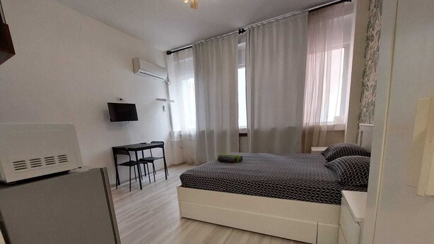 A compact hotel room with a bed, a desk, a chair, and a TV. - Magheru Studio Central (Bucharest)