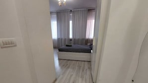 A bedroom with a bed, a window with curtains, and a light switch on the wall. - Magheru Studio Central (Bucharest)