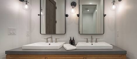 Un baño con dos lavamanos, un mueble de tocador de madera y espejos montados en la pared.