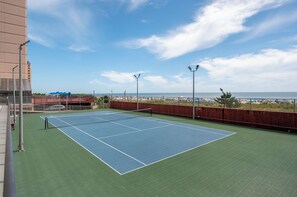 Una cancha de tenis en la azotea con vistas a la playa y al océano.