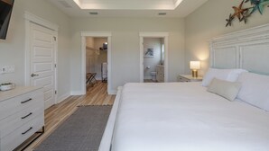 A bedroom with a large bed, a dresser, a nightstand, and a ceiling fan.