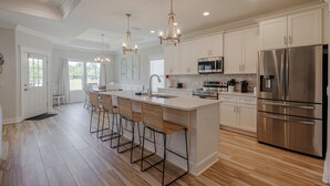 A modern kitchen with a large island, stainless steel appliances, and pendant lighting.