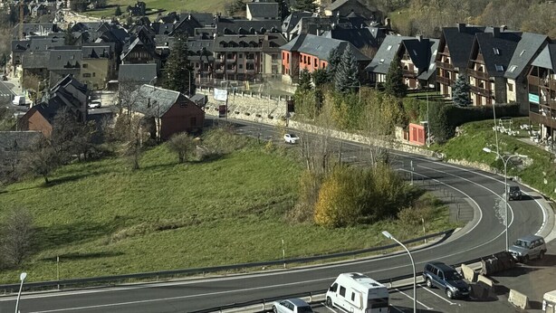 Une ville caractérisée par un clocher d’église imposant, entourée d’immeubles d’habitation et traversée par une route où circulent des véhicules.