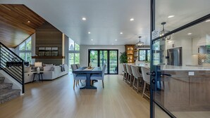 Un'ampia zona giorno con tavolo da pranzo, divano e angolo cottura dotato di elettrodomestici moderni.