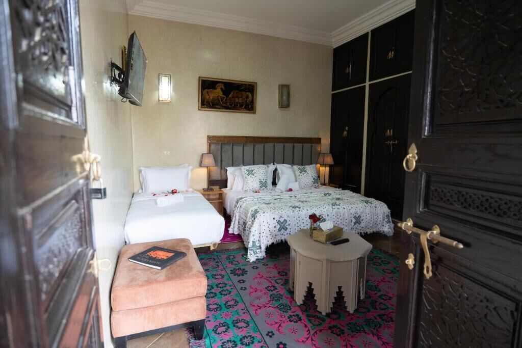 A bedroom with a bed, bedside tables, a small round table, and a door with intricate design.