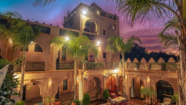 A courtyard with a pool, outdoor seating, and a building with arches and balconies. - riad rayhana de l atlas  (Ourika)