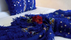 A bed with a blue blanket and a red rose. - riad rayhana de l atlas  (Ourika)