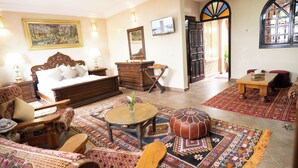 A traditional room with a bed, sofa, wooden furniture, a television, and a patterned rug. - riad rayhana de l atlas  (Ourika)