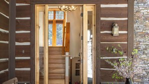 A log cabin interior with a stone fireplace, wooden benches, and a stone wall.