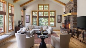 A spacious living room with a stone fireplace, large windows, and a cozy seating area.