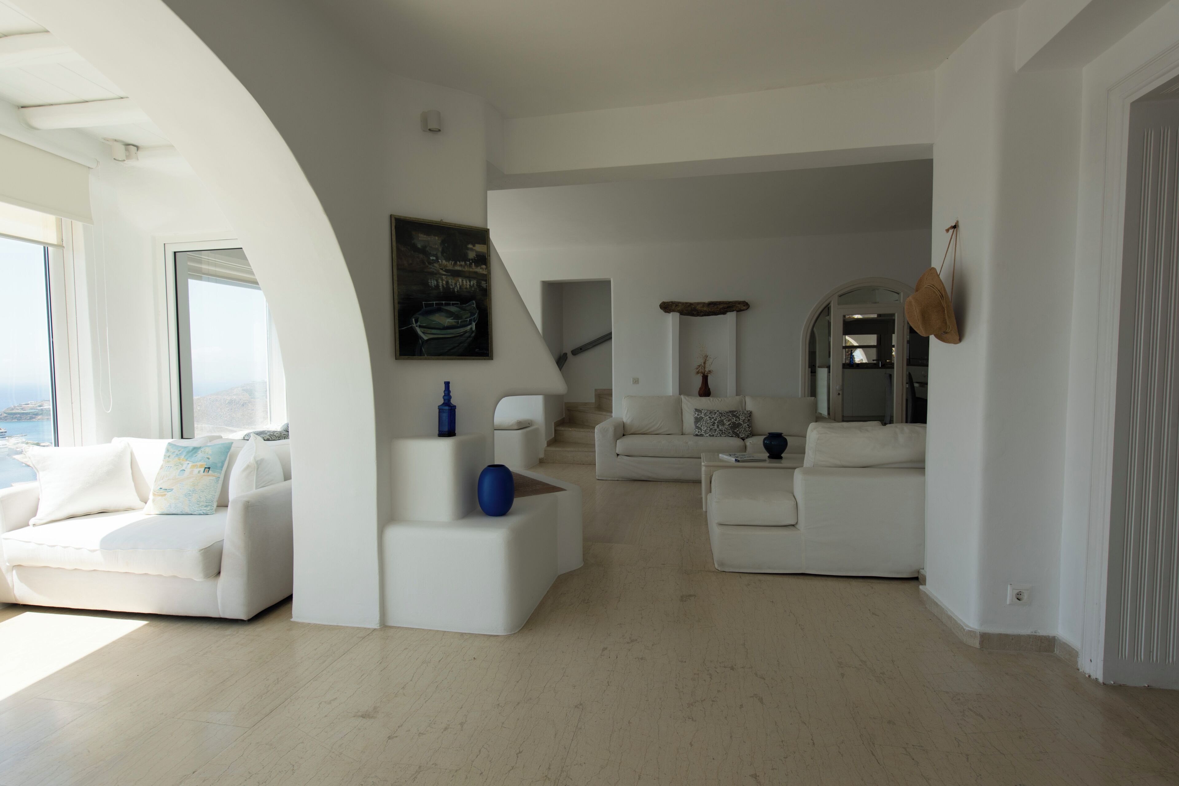 Un salon moderne avec des meubles blancs, une grande fenêtre et une vue sur la mer.