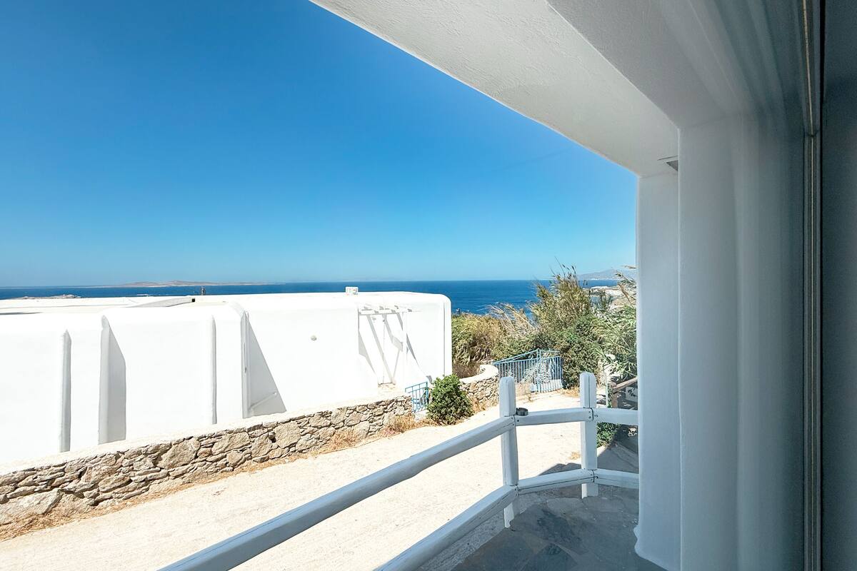 Un balcon avec vue sur la mer et un bâtiment blanc.