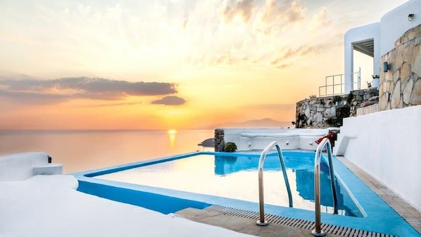 A pool with a sunset view, stone walls, and a clear sky. - Eagles Nest Mykonos Adults Only (Tourlos)