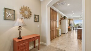 A hallway with a wooden cabinet, a lamp, and framed starfish decorations.