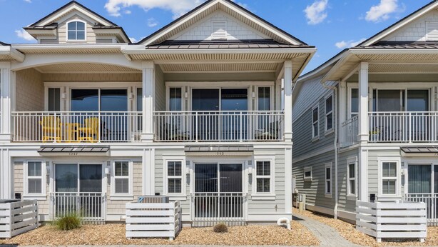 A two-story residential building with a balcony, a garage, and a driveway.
