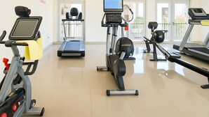 Une salle de sport équipée de divers appareils d’exercice, notamment des tapis de course, un vélo elliptique et un vélo d’appartement.