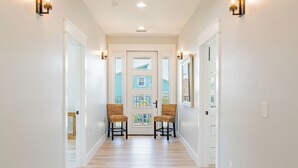 A hallway with two wicker chairs, a white door with glass panels, and wall sconces. - ⛱️Canal Front with Private Pool-Close to Beach-Family Beach House⛱️ (Fort Myers Beach)