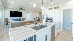A modern kitchen with a marble countertop, stainless steel appliances, and pendant lighting. - ⛱️Canal Front with Private Pool-Close to Beach-Family Beach House⛱️ (Fort Myers Beach)