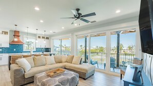 A spacious living area with a large sectional sofa, a patterned ottoman, and a ceiling fan. - ⛱️Canal Front with Private Pool-Close to Beach-Family Beach House⛱️ (Fort Myers Beach)