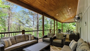An outdoor covered patio with wicker furniture, a fan, and a view of the forest. - NEW Listing! Elevated forest views at Pines Peak! (Broken Bow)