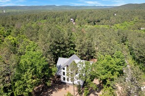 Une maison à deux étages, entourée d’une forêt dense, offrant une vue dégagée sur le paysage environnant.