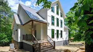 A two-story house with a covered porch and a staircase leading to the entrance. - NEW Listing! Elevated forest views at Pines Peak! (Broken Bow)