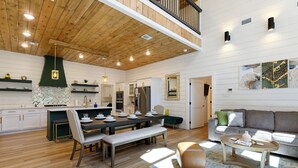A spacious living area with a dining table, benches, and a sofa. - NEW Listing! Elevated forest views at Pines Peak! (Broken Bow)